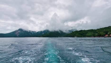 Azure-blue-ocean-boat-wake-in-heavy-cloud-overcast-jungle-mountains
