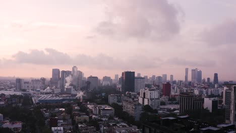 Mexico-city-skyline-with-colorful-sky-above,-aerial-ascend-reveal-shot