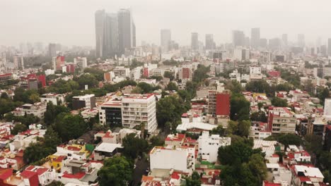Narrow-streets-and-blocks-of-Mexico-city-with-skyscrapers-hiding-in-fog,-aerial-view