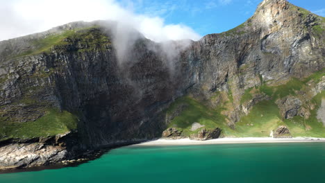 Wide-rotating-aerial-footage-of-a-rocky-coastline-and-beach-in-Vaeroy,-Lofoten-Islands-in-Norway