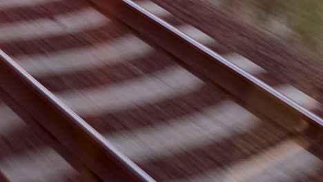 Fast-passing-railway-tracks,-filmed-in-the-back-of-a-train,-looking-down