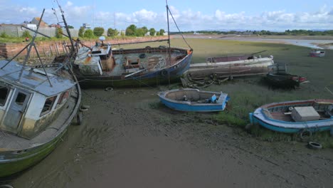 Shipwrecks-on-riverside-at-low-tide,-fast-orbit-with-swallows-flying