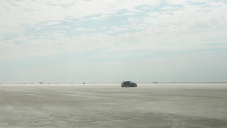 Lonely-Car-Driving-on-a-Large-Beach-in-Fanø,-Esbjerg,-Denmark,-Grey-VW-Polo