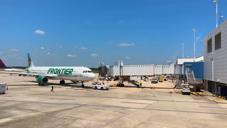 Avión-De-Frontier-Airlines-Estacionado-En-La-Puerta-De-La-Terminal-Del-Aeropuerto-Con-Personal-De-Tierra,-4k