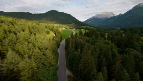 FPV-drone-flying-fast-above-an-empty-alpine-road-in-the-mountains-surrounded-by-a-forest-pine-trees-in-the-region-of-Tyrol,-Austrian-Alps