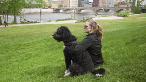 Young-woman-sitting-with-her-dog-inn-a-city-park