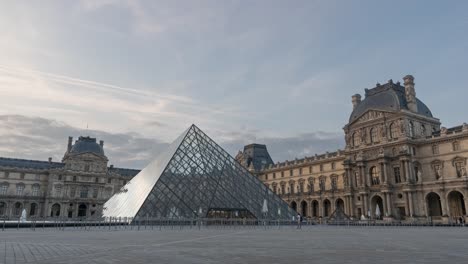 Lapso-De-Tiempo-Del-Museo-Del-Louvre-Por-La-Mañana,-Capturando-El-Amanecer,-La-Icónica-Pirámide-De-Cristal-Y-Los-Primeros-Visitantes-En-París