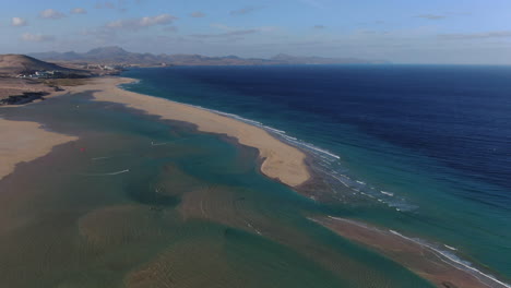 La-Barca-beach,-Fuerteventura:-panoramic-and-orbital-aerial-view-over-the-beautiful-beach-and-turquoise-waters