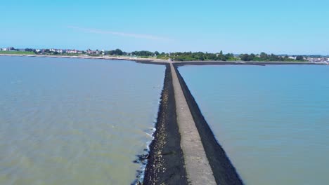 drone-fly-above-harwich-lighthouse-revealing-aerial-seascape-with-beach-and-ocean-water-during-a-sunny-day-in-England-Essex-UK