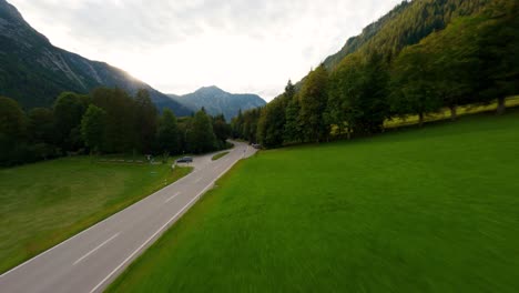 Aerial-FPV-drone-shot-flying-above-an-empty-alpine-road-in-the-mountains-surrounded-by-a-forest-pine-trees-in-an-Alpine-landscape