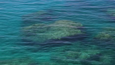 Tiefes-Türkisfarbenes-Meerwasser,-Das-Durch-Eine-Leichte-Brise-An-Der-Küste-Des-Wunderschönen-Mittelmeers-Weht,-Felsen-Und-Kieselsteine-Unter-Wasser,-Meereslandschaftshintergrund