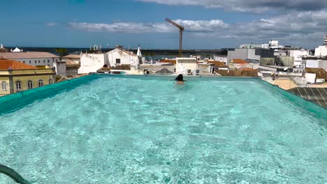 A-woman-swims-in-an-outdoor-pool-nestled-in-the-heart-of-Faro,-Algarve