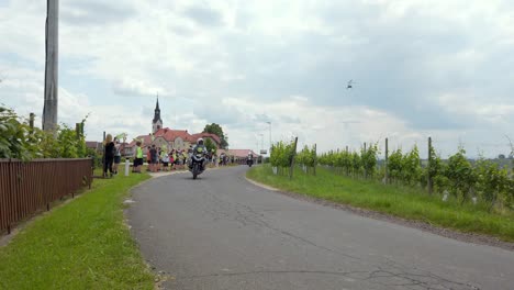 Atemberaubende-HD-Aufnahmen-Von-Radfahrern,-Die-An-Einer-Tour-Durch-Slowenien-Teilnehmen-Und-Durch-Svetinje-Und-Weinberge-Radeln,-Während-Fröhliche-Kinder-Entlang-Der-Straße-Sie-Anfeuern