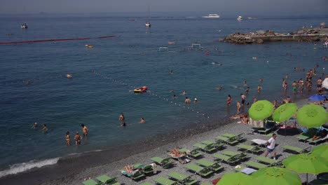 Escena-De-Turistas-Tomando-El-Sol-Y-Disfrutando-De-La-Diversión-Acuática-A-Lo-Largo-De-La-Famosa-Playa-De-Camogli,-Italia