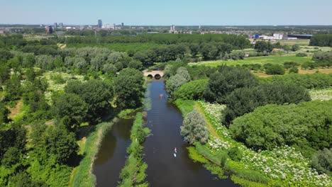 Aerial-drone-parallax-shot-above-a-nature-park,-water-canal,-of-Almere-city,-province-Flevoland,-Netherlands