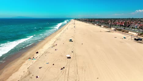 Drone-flying-over-Huntington-Beach-with-almost-no-people-and-some-large-waves-breaking-on-the-shore