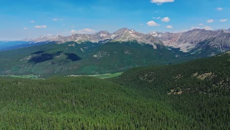Aerial-over-the-trees-and-hills-of-Cottonwood-Pass-with-the-Rocky-Mountains-in-the-background,-Colorado,-USA