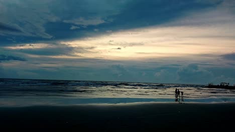 Silhouettes-of-children-happily-playing-in-the-beach-on-a-majestic-blue-sunset-in-Dipolog-Philippines,-wide-view