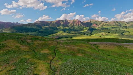 Aerial-over-green-hills-near-the-Crested-Butte-mountain,-Colorado,-USA