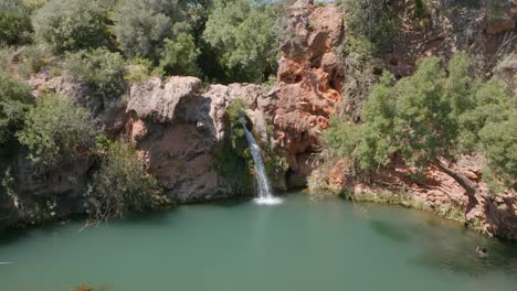 Cascata-do-Pego-do-Inferno-waterfall-cascades-into-turquoise-pool-of-water-by-rope-swing,-algarve-portugal