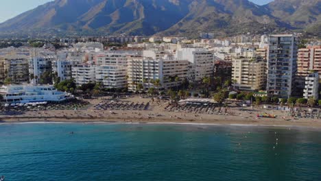 Drone-shot-backing-out-over-the-water-from-the-beach-at-Marbella,-Spain