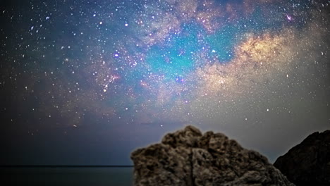 Der-Zeitraffer-Fängt-Kometen-Ein,-Die-über-Einem-Felsbrocken-über-Den-Nachthimmel-Streifen,-Mit-Dem-Meer-Im-Hintergrund