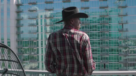 Black-man-with-black-cowboy-hat-looking-out-from-balcony