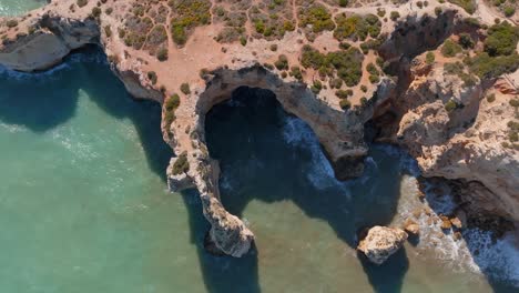 Drone-top-down,-Praia-da-Marinha-scenic-coastline-at-midday,-shadows-on-ocean