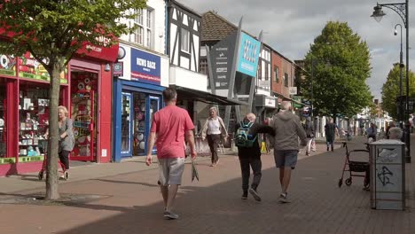 Slow-motion-people-walking-down-British-Cheshire-town-passing-shops-in-high-inflation-cost-of-living-crisis