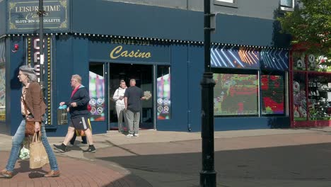 Slow-motion-people-walking-in-British-town-passing-gambling-casino-during-high-inflation-cost-of-living-crisis