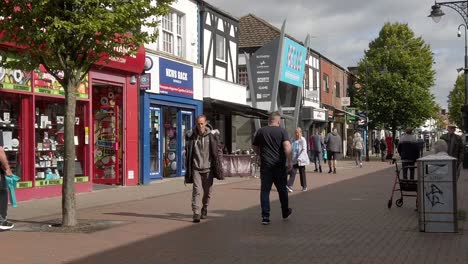 Slow-motion-pedestrians-walking-down-British-Cheshire-town-street-passing-shops-in-high-inflation-cost-of-living-crisis