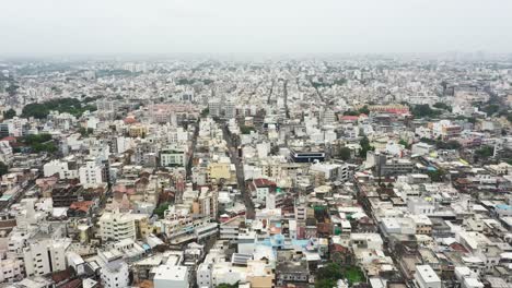 Aerial-drone-camera-of-Rajkot-city-panning-around-showing-old-houses,-lowrise-buildings,-temples,-street-markets,-and-tall-highrise-buildings