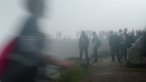 View-of-the-Pulpit-Rock,-Preikestolen-in-Norway,-A-lot-of-Tourists-Taking-Pictures-on-a-Cloudy-Foggy-Day,-Mass-tourism-in-Bad-Weather,-Slow-Shutter-Effect