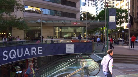 Dynamic-zoom-in-shot-capturing-large-crowd-of-office-workers-taking-the-escalator-down-to-the-food-court-at-post-office-square-during-busy-lunch-time-rush-hours,-Brisbane's-central-business-district