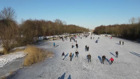 Drone-shot-of-a-large-group-of-people,-skating-on-natural-ice-in-the-Netherlands