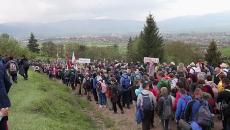 Gente-Caminando-Cuesta-Abajo-Después-De-La-Peregrinación-A-Csiksomlyo,-La-Montaña-Miercurea-Ciuc-Harghita-Al-Fondo