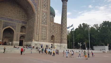 Kids-Playing-in-Front-of-Sher-Dor-Madrasa,-Everyday-Life-in-Samarkand-Uzbekistan
