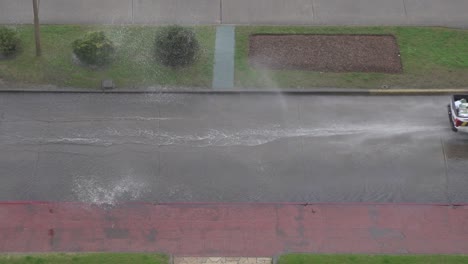 Aerial-top-down-shot-of-police-car-driving-by-flooded-street-in-rain,-Uruguay