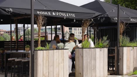 Gente-Feliz-Saliendo-Y-Hablando-En-La-Terraza-Del-Restaurante-De-Pollo-Poule-And-Poulette-En-La-Ciudad-De-Amberes,-Bélgica.