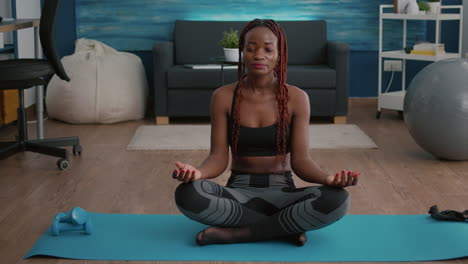 Portrait-of-black-woman-sitting-in-lotus-position-on-floor-doing-morning-breathing-workout