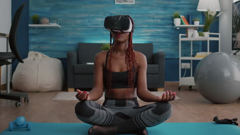 Mujer-Negra-En-Forma-Con-Casco-De-Realidad-Virtual-Mientras-Está-Sentada-En-El-Mapa-De-Yoga