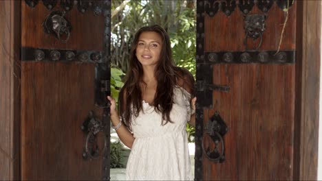 Cheerful-woman-opening-old-wooden-doors