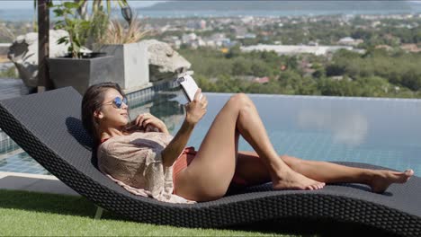 Lounging-female-taking-selfie-at-poolside-on-top-of-hotel