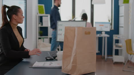 Businesswoman-holding-paper-bag-with-takeaway-food-meal-order-putting-on-desk