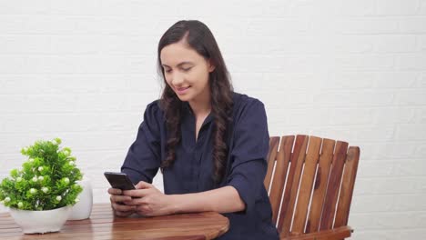 Indian-girl-scrolling-phone-at-a-cafe