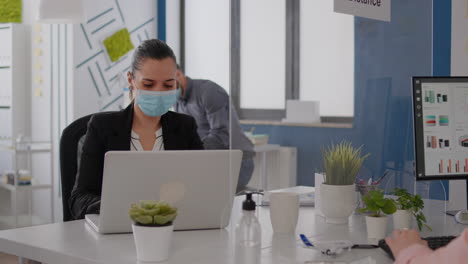 Business-team-with-medical-face-masks-working-together-in-startup-company-office