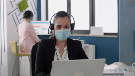 Businesswoman-with-protection-face-mask-talking-into-microphone