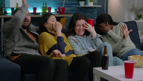 Group-of-mixed-race-people-sitting-comfortable-on-sofa-while-looking-at-thriller-movie