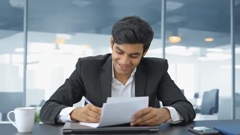 Happy-Indian-businessman-reading-and-signing-the-contract