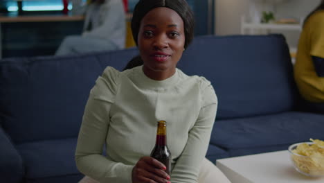 Closeup-of-black-woman-portrait-looking-into-camera-drinking-beer-for-friend-birthday